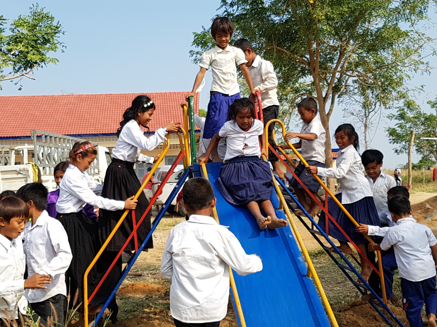 Children playing on a brightly coloured slide at a school playground in rural Battambang, Cambodia