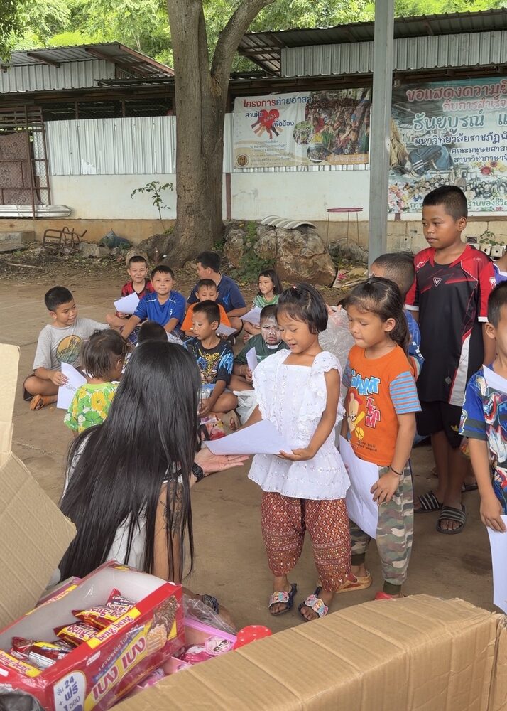 Children gathered around the supplies at Tham Charoen Suk